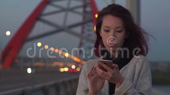 有魅力的女人在夜城街道上散步时讲手机视频的预览图