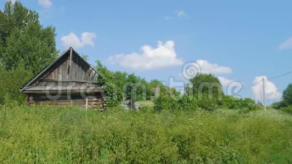 在茂密的绿草灌木丛中有奴隶般屋顶的废弃房子的景色视频的预览图