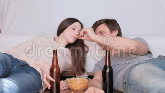 几个年轻的男人和女人吃薯片喝啤酒看电视视频的预览图