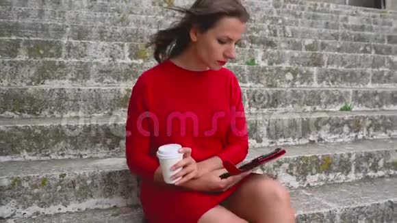 坐在户外台阶上看电子书的女人视频的预览图