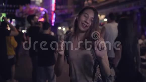 慢动作年轻的亚洲旅游妇女背包客喝酒或啤酒并在城市街头夜间聚会跳舞视频的预览图