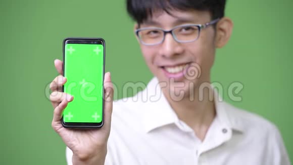 年轻的亚洲商人带着手机拍照视频的预览图