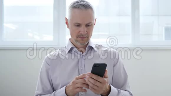 中年男子在使用智能手机时为损失烦恼视频的预览图