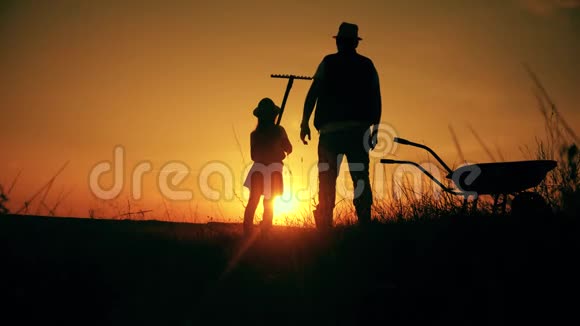 父亲和女儿的剪影与土地运输和耙子工具小规模有机农业视频的预览图