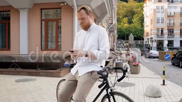4k视频时尚潮男坐在自行车上手机打字视频的预览图
