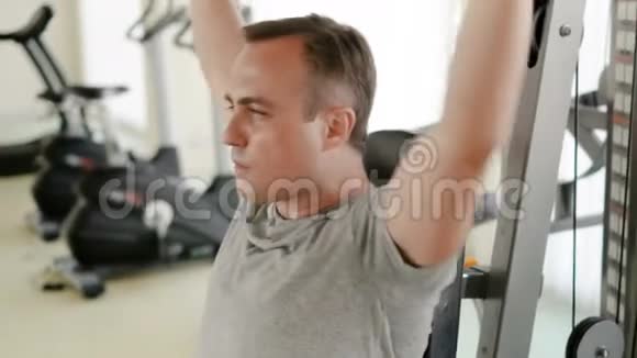 有决心的运动青年穿着灰色t恤在健身房锻炼举重机视频的预览图