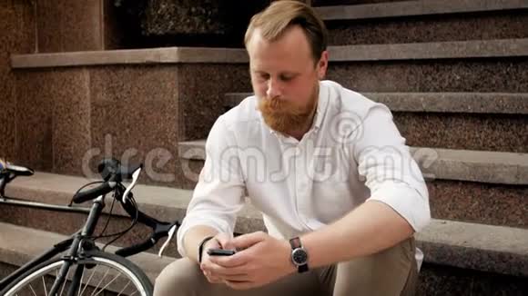 4k视频坐在石阶上用智能手机笑红胡子男子视频的预览图