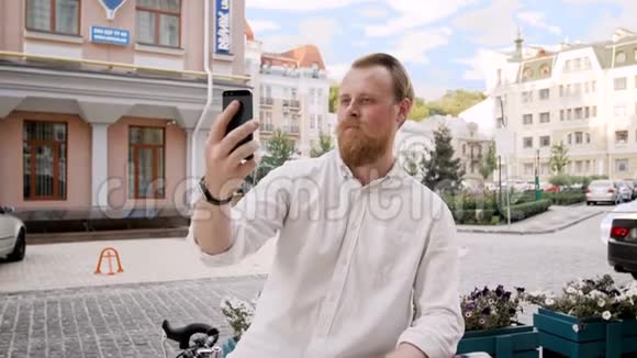 4k镜头时尚留胡子的男人靠在他的双脚上使用智能手机视频的预览图