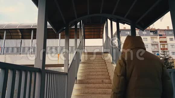 一个穿着米色外套的男人跑上人行桥的楼梯视频的预览图