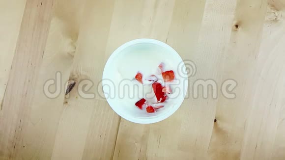 男人用勺子在木桌上慢动作地吃健康的草莓和白色酸奶健康食品的概念视频的预览图