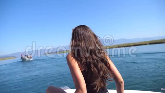 年轻女孩坐在船首的后景在旅途中寻找美丽的自然景观快乐的女人视频的预览图