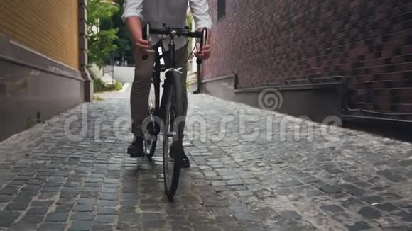 4K镜头年轻的嬉皮士骑着黑色自行车在狭窄的街道上视频的预览图