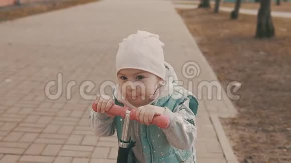 小女孩在人行道上慢动作地骑着粉色滑板车视频的预览图