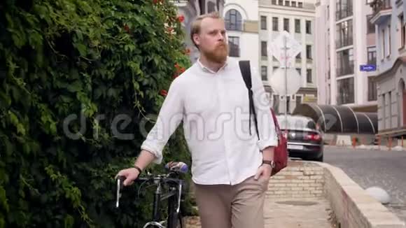 4k镜头时尚红胡子男子骑自行车在街上行走视频的预览图