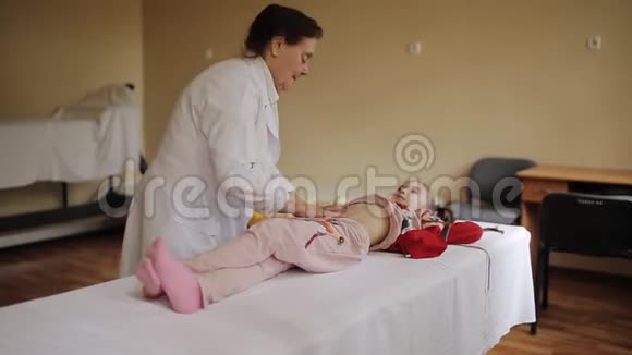 一位老年妇女医生在医院的按摩室里做了一个小腹部按摩女孩视频的预览图