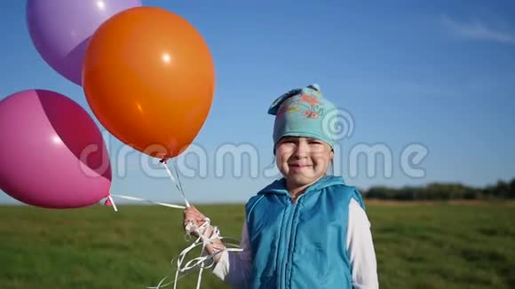 可爱的女孩站在田里拿着气球视频的预览图