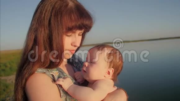 婴儿抱着一位年轻的母亲微笑着慢动作视频的预览图