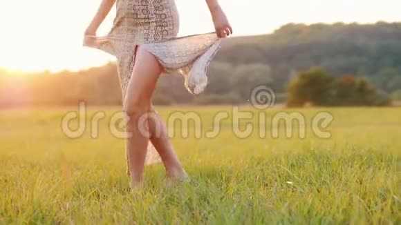 年轻女子穿着一件轻薄的连衣裙裙子从落日的余晖中闪过视频的预览图