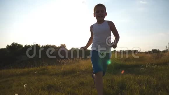 快乐的小男孩在镜头后的田野里奔跑的肖像微笑的男孩子在夏天的草地上享受大自然的乐趣视频的预览图