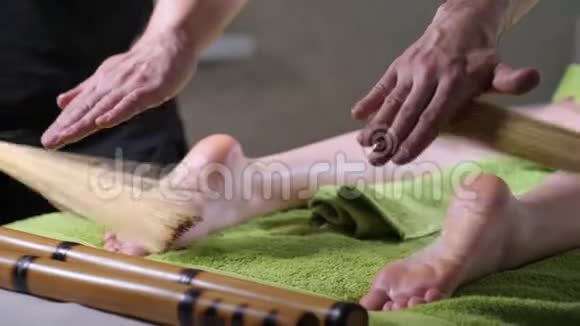 两个男按摩师和女人一起工作日本脚按摩用竹棒在水疗沙龙人美健康视频的预览图