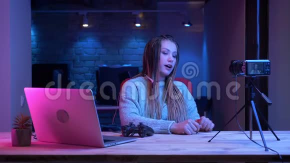 有魅力的年轻女性博客写手在耳机里用可怕的声音进行特写镜头现场直播谈论电子游戏视频的预览图