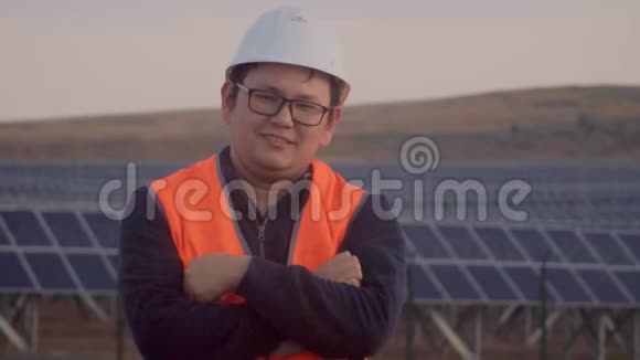 一个穿着工程师服的亚洲人在太阳能发电厂的背景下看着地平线视频的预览图