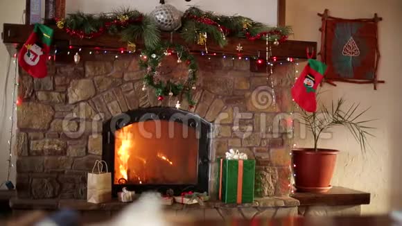 在圣诞前夜壁炉里燃烧着花环花环长袜和礼品盒新年视频的预览图