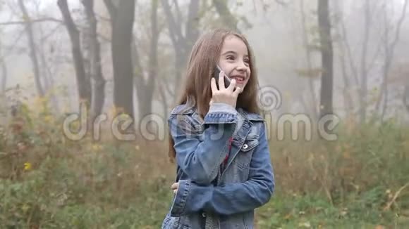 快乐美丽的女孩在森林边走边打电话视频的预览图