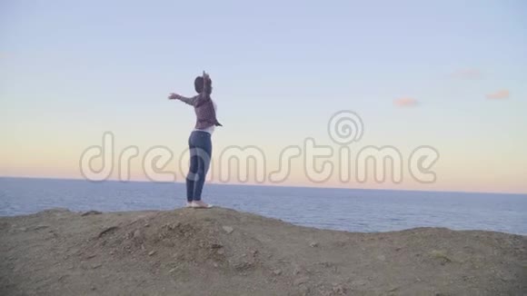 年轻女子站在山顶望着大海日落视频的预览图