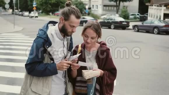 年轻的幸福夫妇拿着棋盘游戏的盒子嬉皮士男女在市中心玩探索视频的预览图