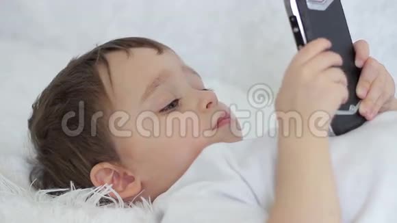小孩躺着玩智能手机视频的预览图