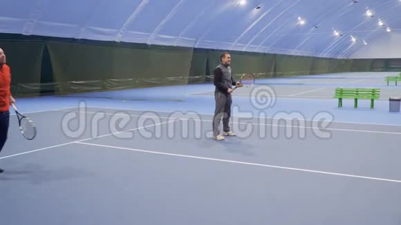 两个白种人在室内球场打网球视频的预览图