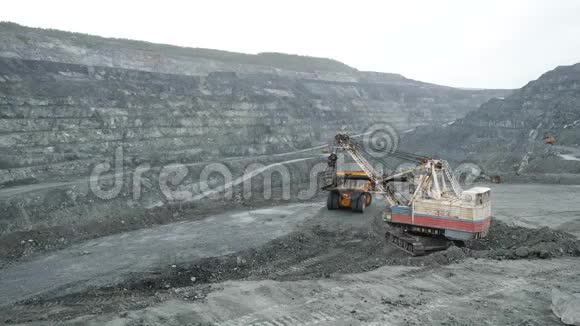 挖掘机在露天坑内用土填满自卸汽车露天采矿工业重型机械工程视频的预览图