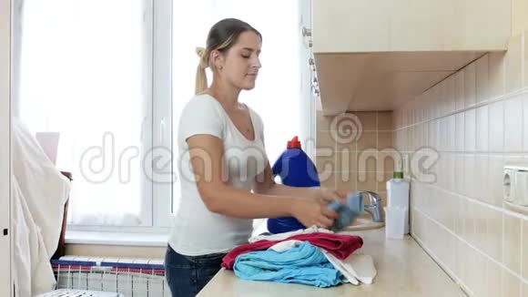 4k视频美丽的年轻女子折叠和携带干净的衣服从洗衣房视频的预览图
