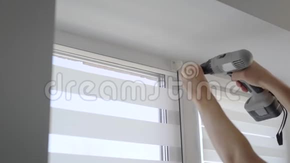 在一间现代化的公寓里一个熟练的人正在旋转用重新充电的螺丝刀固定窗户上的紧固件视频的预览图