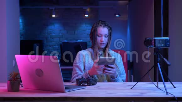 有魅力的年轻女性博客写手在耳机里用可怕的声音进行特写镜头现场直播谈论电子游戏视频的预览图