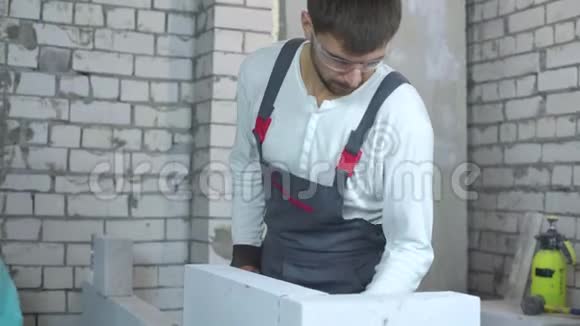 年轻男建筑工人检查加气混凝土墙体的均匀度视频的预览图