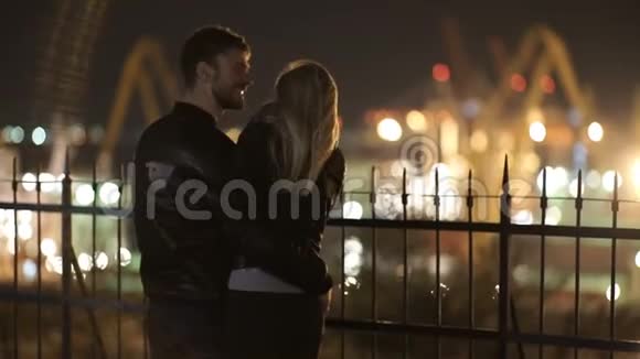 在港口灯光的背景下一对漂亮的情侣拥抱在一起享受夜晚的亲密时光视频的预览图
