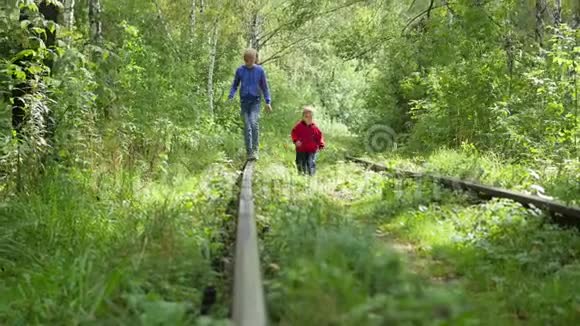 一个孤独的十几岁男孩和他的弟弟正在火车轨道上行走视频的预览图