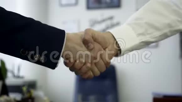 商务人士握手作为协议的标志关闭以便与办公室的两位业务伙伴握手视频的预览图