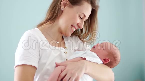 母亲怀里抱着一个新生婴儿女人微笑轻轻地抚摸他母亲的幸福母亲视频的预览图