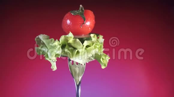用新鲜的红番茄切片和黄瓜叉在水滴里生菜旋转红色背景视频的预览图