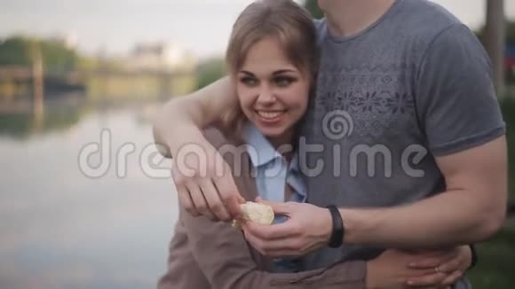 在河边的约会中找到一男一女美丽的女孩打破面包扔进水里视频的预览图