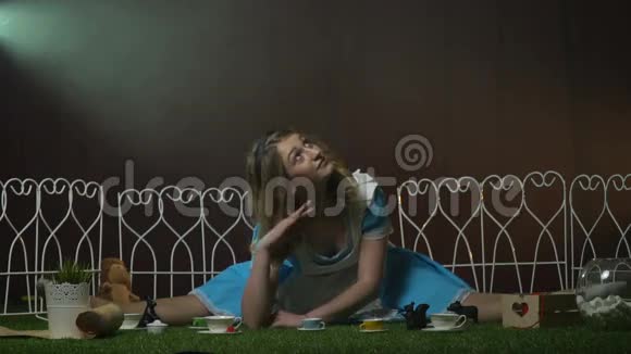 有趣的爱丽丝坐在草地上拿着茶具视频的预览图