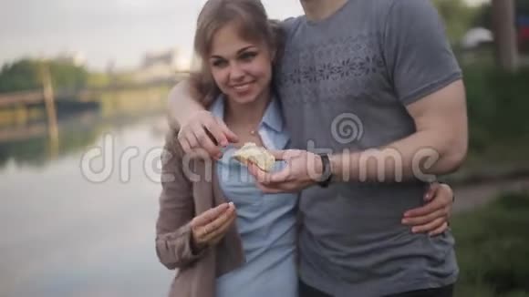 情人一个男人和一个女孩在河边约会美丽的女孩打破面包扔进水里视频的预览图