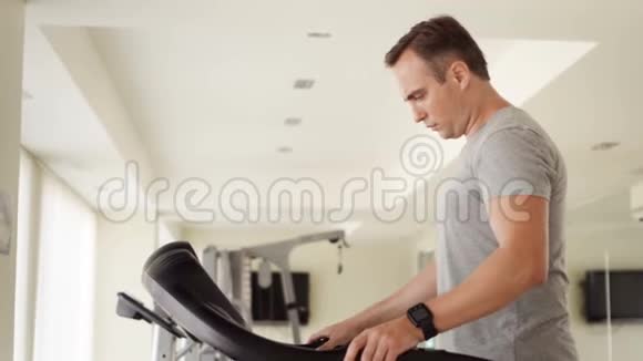 一个穿着灰色T恤在健身房跑步锻炼的英俊青年视频的预览图