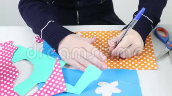 女孩的手在彩纸上画花在手工上剪花视频的预览图