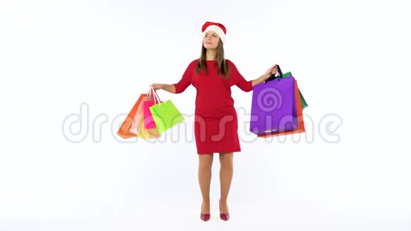 圣诞女购物者拿着五颜六色的购物袋在工作室里疯狂地在白色背景上跳舞走吧视频的预览图