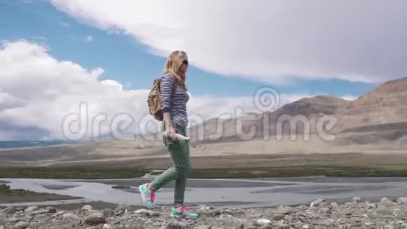 旅行者穿过山区女游客带着背包戴着太阳镜背景视频的预览图