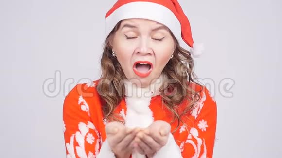 一个戴着圣诞老人帽子的滑稽年轻女子对着纸屑打喷嚏视频的预览图